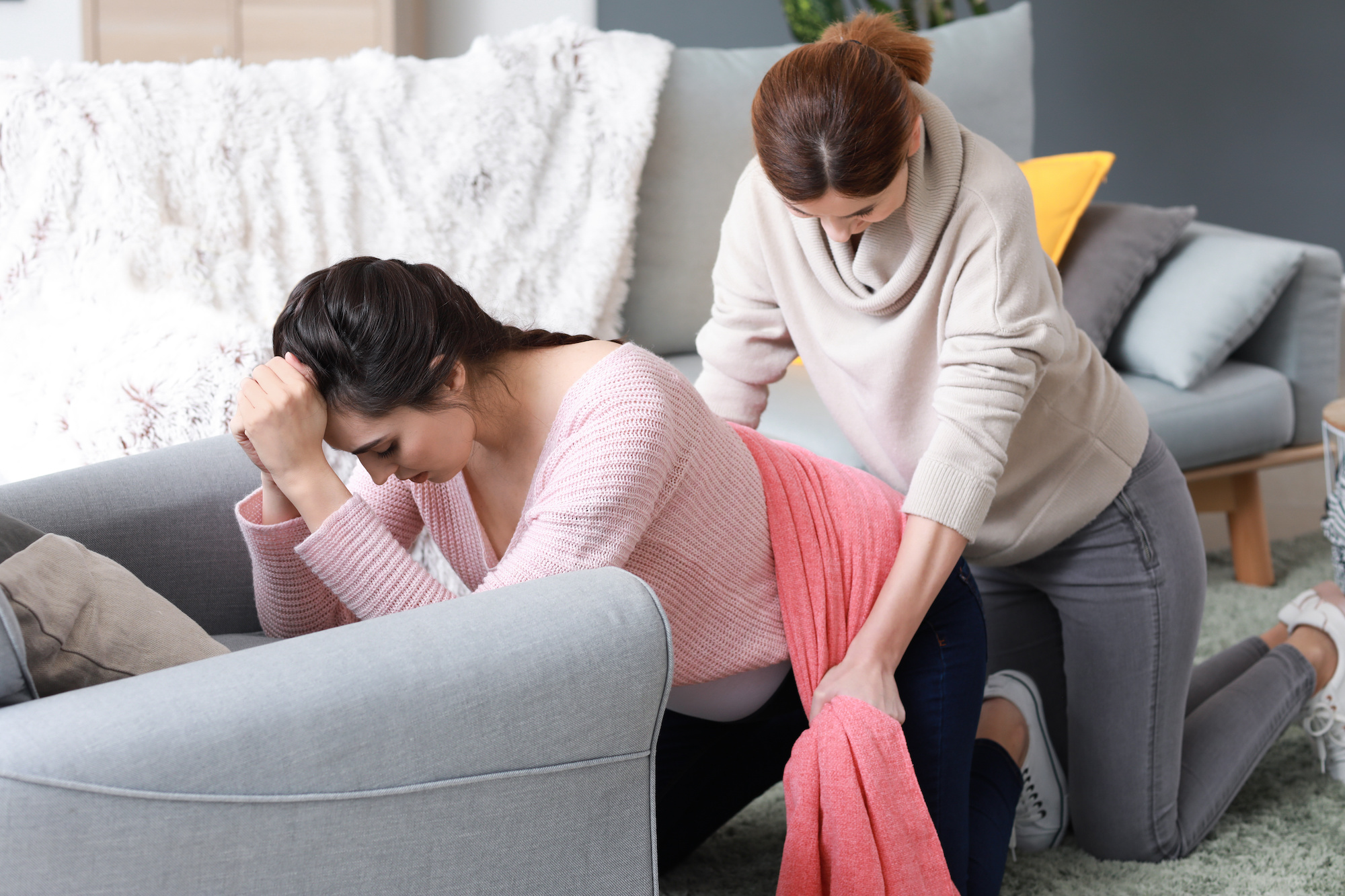 Doula massiert schwangere Frau